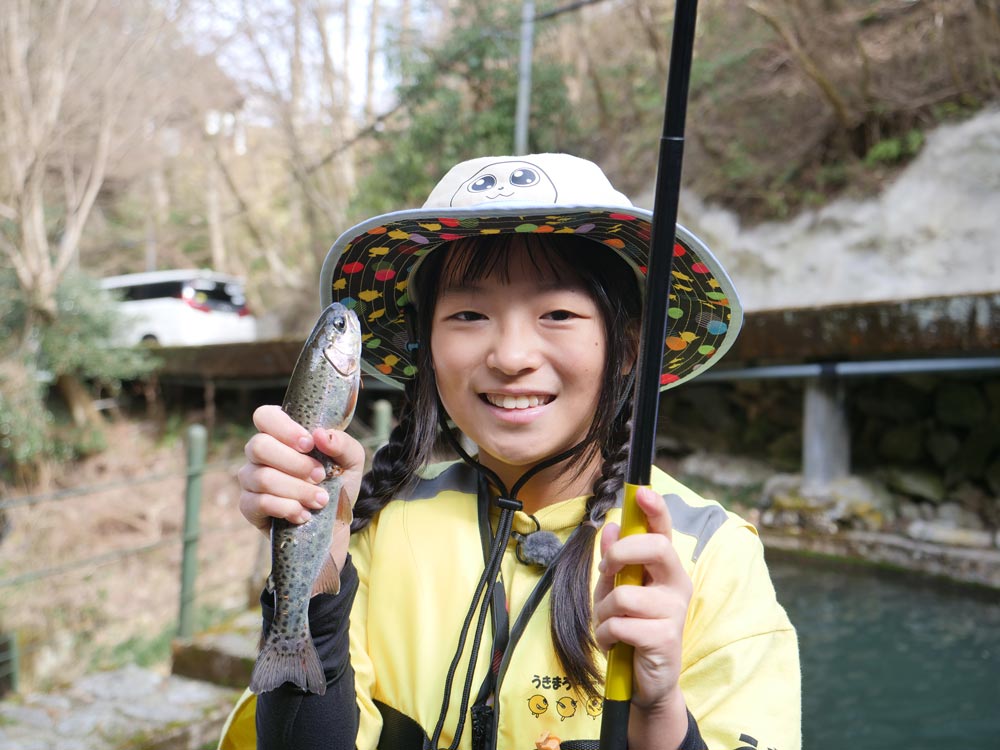 管理釣場で釣れた魚を手に、笑顔を見せる女の子
