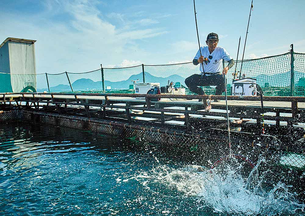 水面に浮かせた魚をタモ網へ収めようとする林